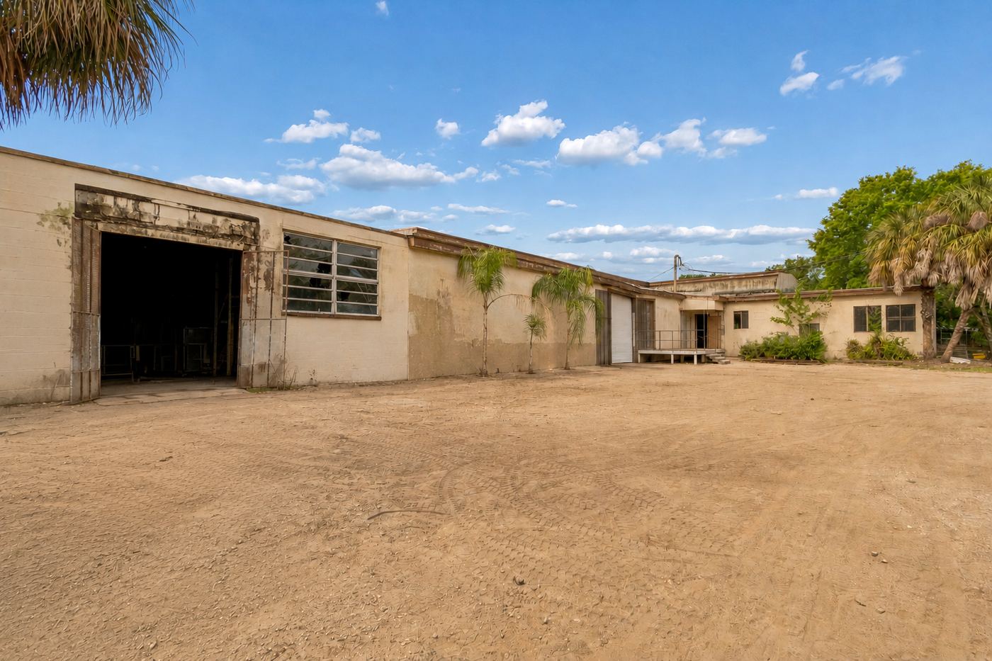 Current condition: weathered facade, dirt yard, original openings at Suite 9