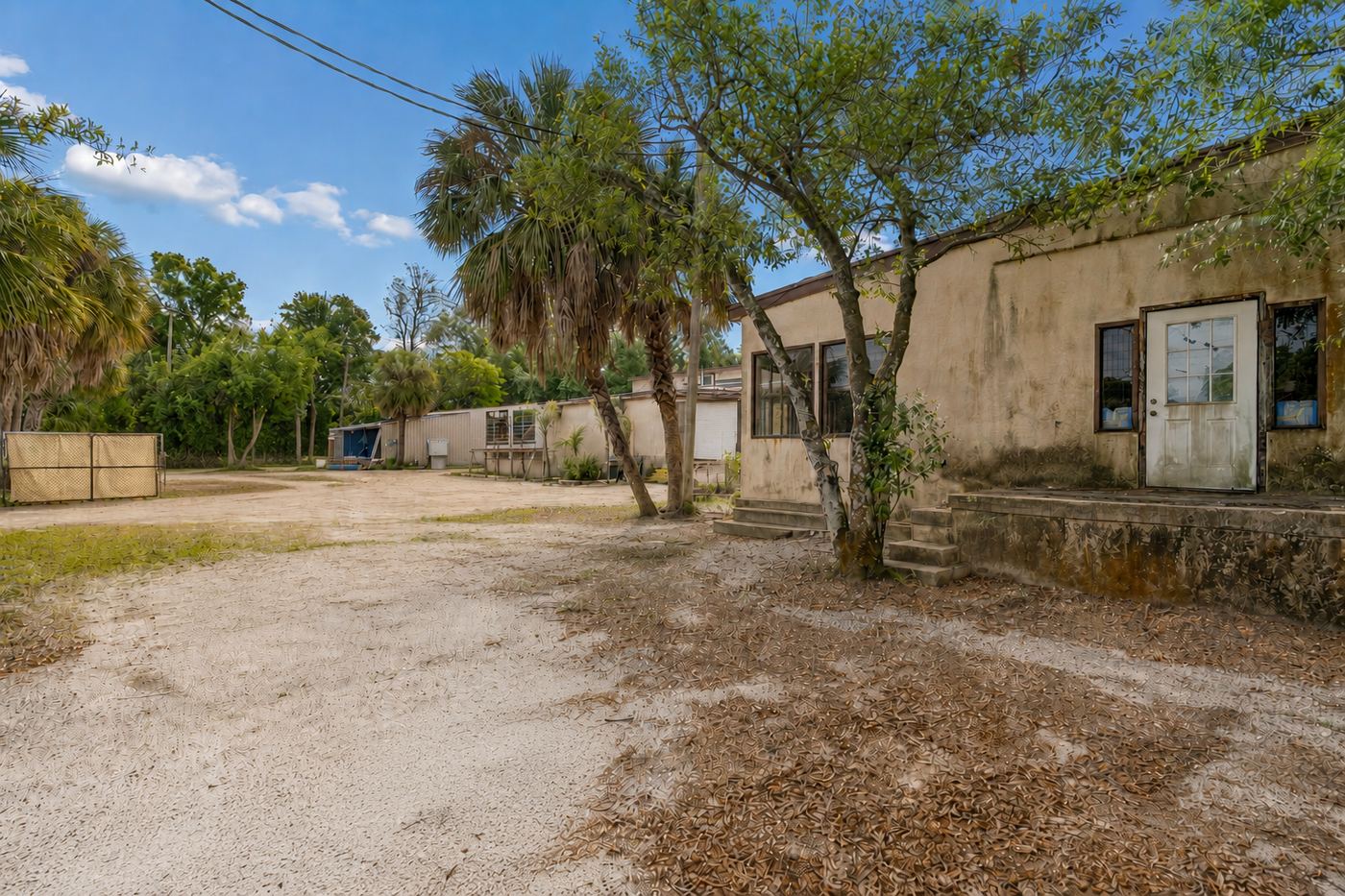 Current condition: weathered stucco, aged entry door, bare dirt approach at Suite 8