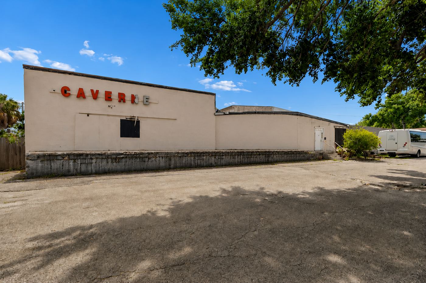 Current condition: faded CAVERNE signage, weathered elevation, aged dock wall and cracked asphalt